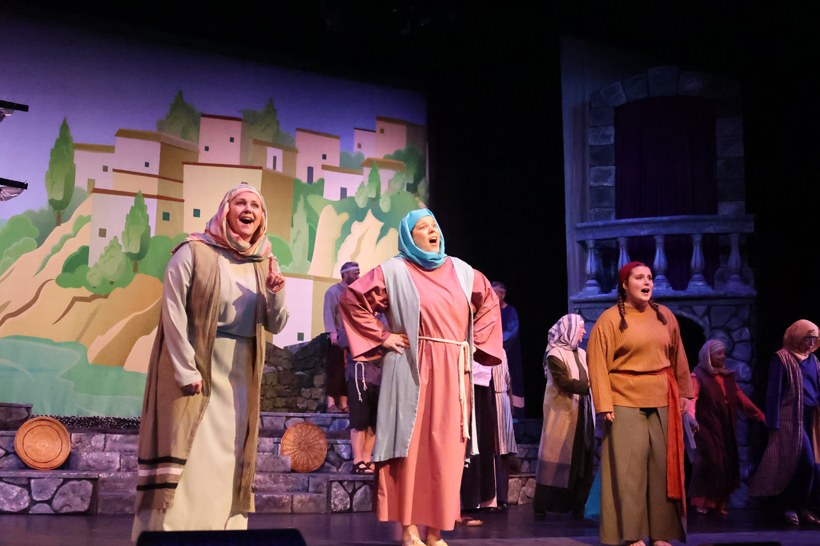 A crowd sings in a biblical seashore setting.